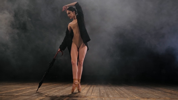 Ballerina in Black Long Jacket and Sexy Bodysuit Dancing on Stage with Magic Light and Smoke alt