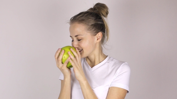 Attractive Young Girl Bites a Big Green Apple