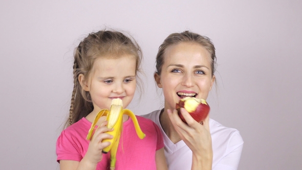 Beautiful Daughter and Mother Are Eating Fruits and Smiling