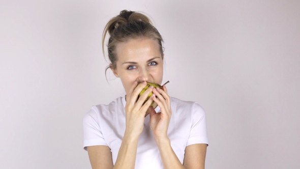 Beautiful Young Woman Bites Juicy Pear