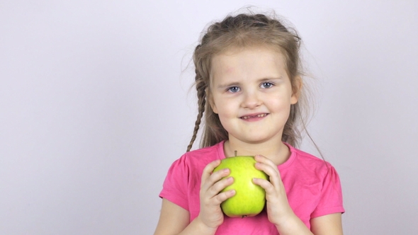 A Young Girl Is Holding a Big Green Apple