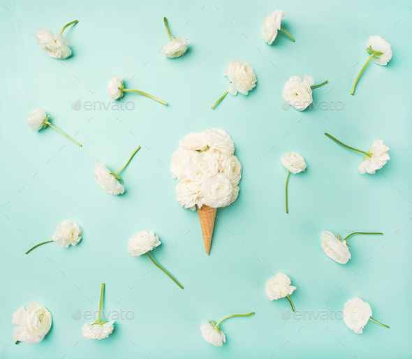 Waffle cone with white buttercup flowers over blue background - Stock Photo - Images