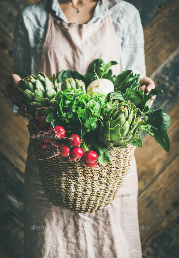Female farmer holding basket of fresh garden vegetables and greens - Stock Photo - Images