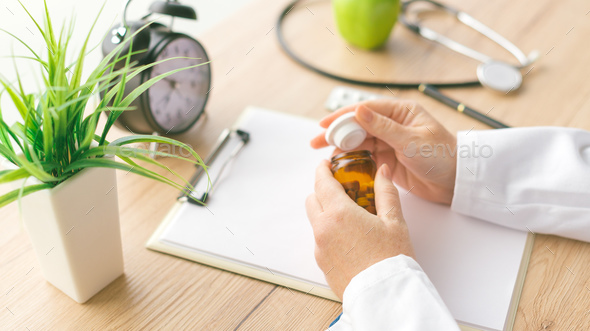 Female doctor holding unlabeled bottle of various pills and medi - Stock Photo - Images