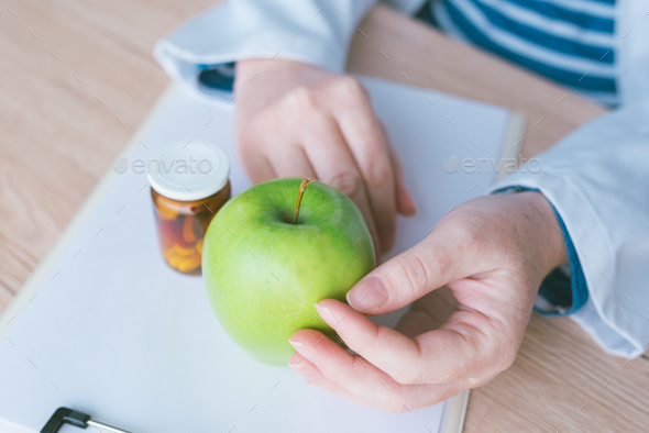 Doctor advising apple instead of pills and antibiotics - Stock Photo - Images