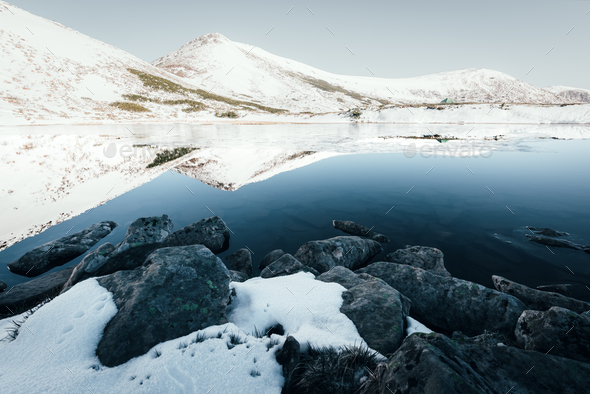 Frozen mountain lake with blue ice - Stock Photo - Images