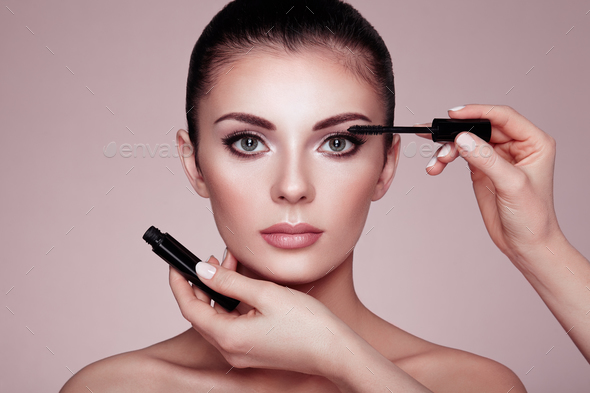 Beautiful brunette woman paints the eyelashes - Stock Photo - Images