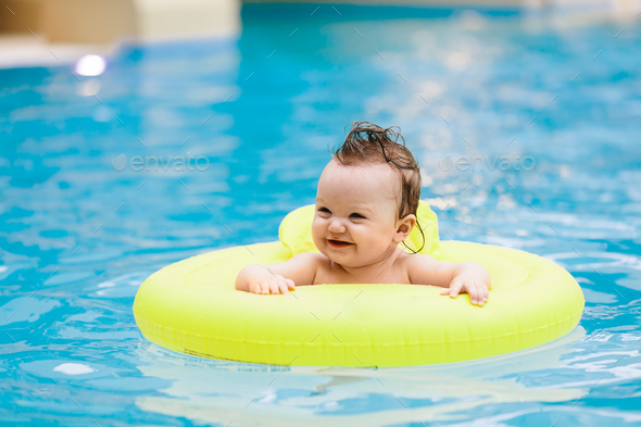 Sweet toddler swimming in a floating ring Stock Photo by photocreo