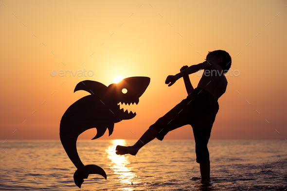 One happy little boy playing on the beach at the sunset time. - Stock Photo - Images