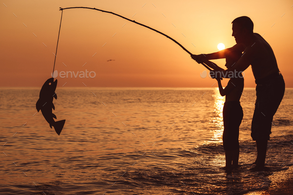 Father and son playing on the beach at the sunset time. - Stock Photo - Images