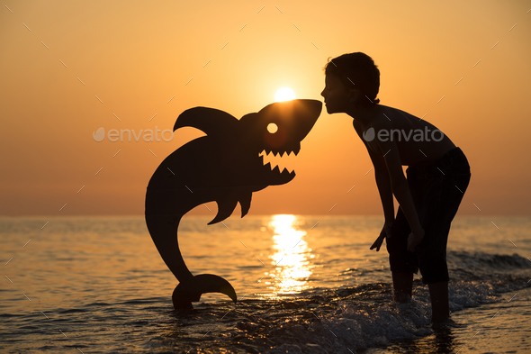 One happy little boy playing on the beach at the sunset time. - Stock Photo - Images