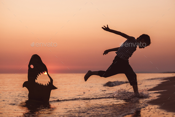 One happy little boy playing on the beach at the sunset time. - Stock Photo - Images