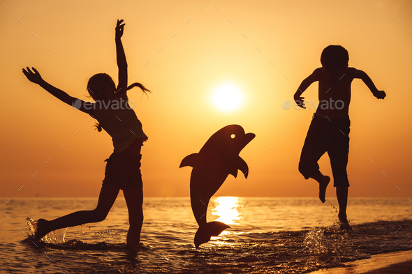 Happy children playing on the beach at the sunset time. - Stock Photo - Images