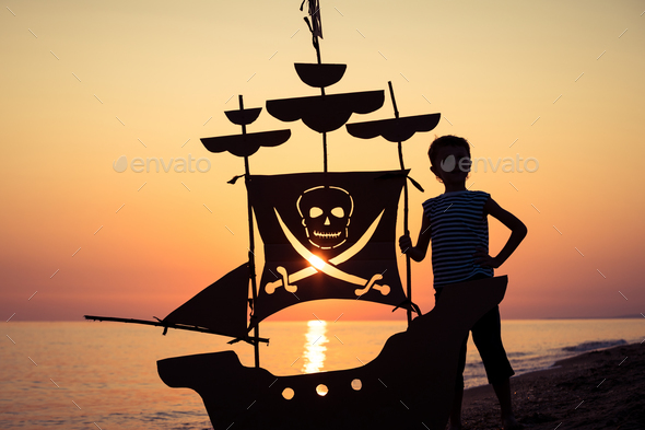 One happy little boy playing on the beach at the sunset time. - Stock Photo - Images