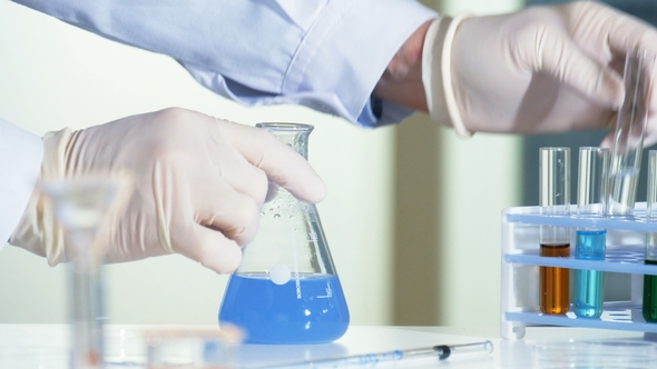 Scientist Pours Chemicals From a Test Tube Into a Flask, Triggering an Intense Chemical Reaction