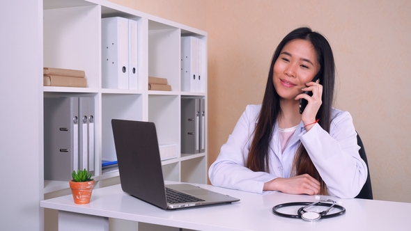 Cardiologist Consults By Phone in Office with White Interior alt