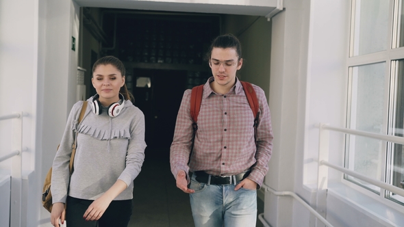 Two Female and Male Students Are Walking in University Hall Discussing Something alt