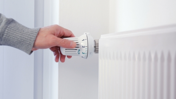 Hand Adjusts the Heating Thermostat