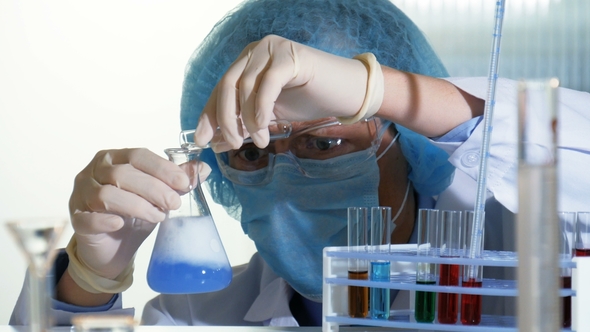 Researcher Pours Chemicals From a Test Tube Into a Flask