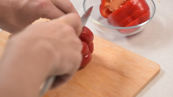 Man's Hand Gently and Slowly Cuts Red Sweet Pepper into Slices with a Knife