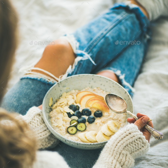 Woman in jeans and sweater eating vegan breakfast, square crop - Stock Photo - Images