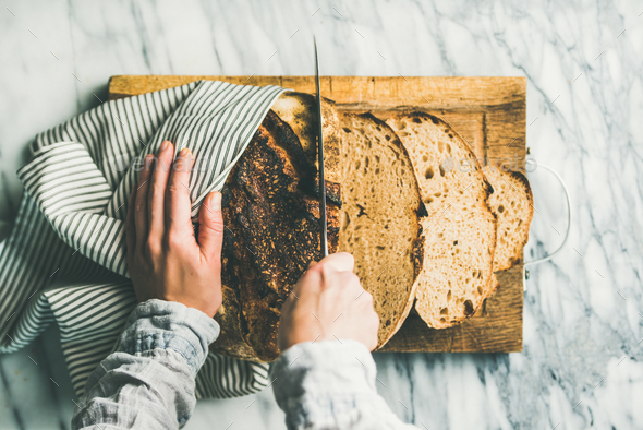 Female hands cutting freshly baked sourdough bread - Stock Photo - Images