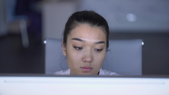 of an Asian Female Person Looks at Monitor and Analyzes Data. alt