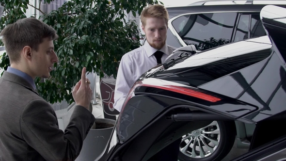 Male Manager Opening Trunk of Car To Show It To the Customer in Autocenter alt