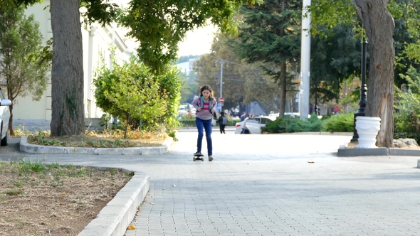 The Girl Is Riding on a Skateboard in the Park
