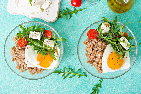 Healthy breakfast with egg, feta cheese, arugula, tomatoes and buckwheat porridge - Stock Photo - Images