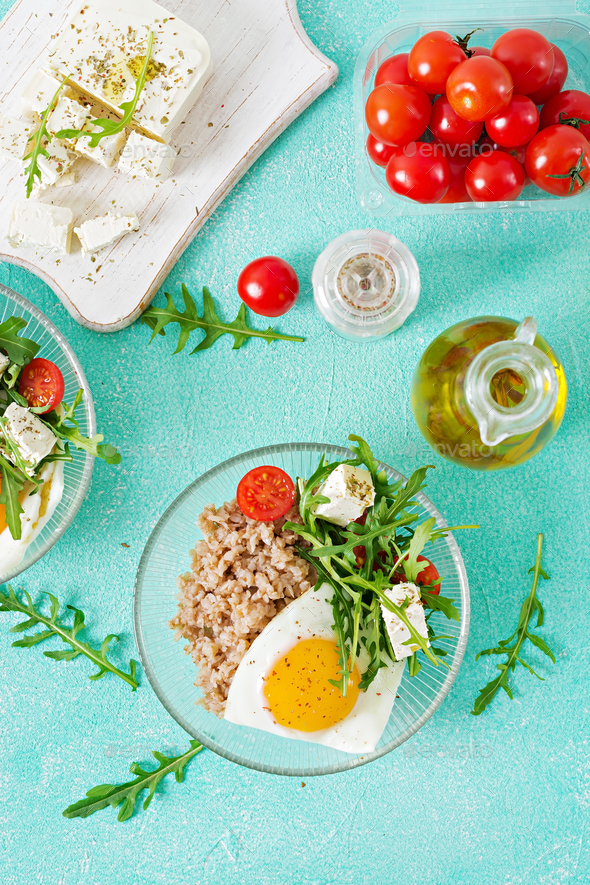 Healthy breakfast with egg, feta cheese, arugula, tomatoes and buckwheat porridge - Stock Photo - Images