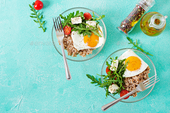 Healthy breakfast with egg, feta cheese, arugula, tomatoes and buckwheat porridge - Stock Photo - Images