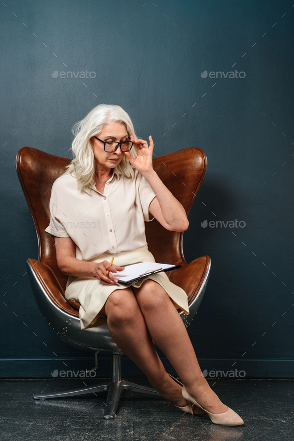 Serious mature old woman holding clipboard - Stock Photo - Images