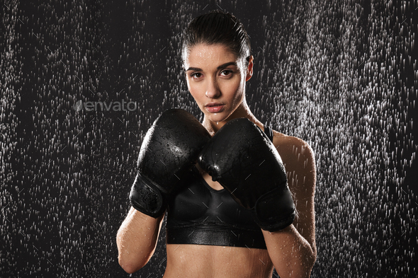 Strict woman doing sports and boxing in gloves while standing in Stock Photo by vadymvdrobot