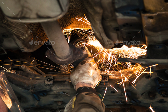 serviceman cleans muffler pipe by angle grinder - Stock Photo - Images