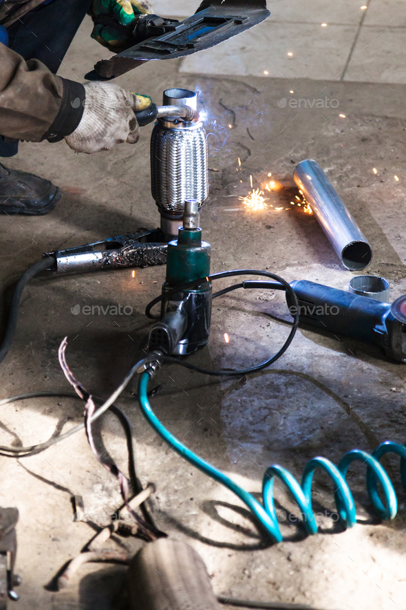 welder fixes pipe on corrugation muffler - Stock Photo - Images