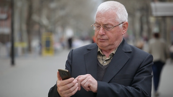 A Wise Man Logs on the Web on His Mobile in a City Street in Spring