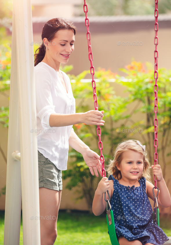 Mom rocks her daughter on a swing - Stock Photo - Images