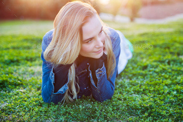 Pretty girl lying down on green grass - Stock Photo - Images