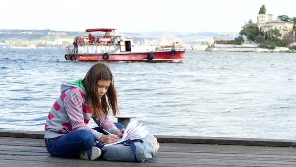The Girl Is Doing Homework on the Quay Near the Sea