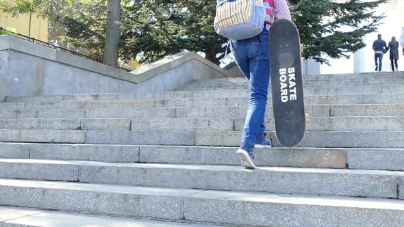 A Girl Climbs the Steps and Holds a Skateboard in Her Hand