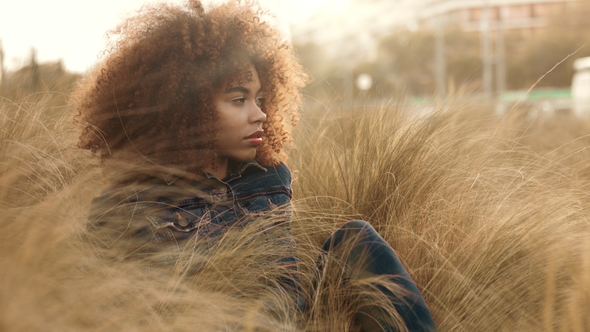 Black Mixed Race Woman with Big Afro Curly Hair in Lawn Field with High Dry Autumn Hay Grass and