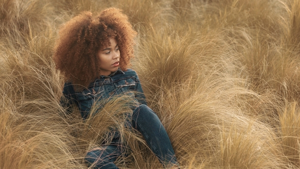 Black Mixed Race Woman with Big Afro Curly Hair in Lawn Field with High Dry Autumn Hay Grass and