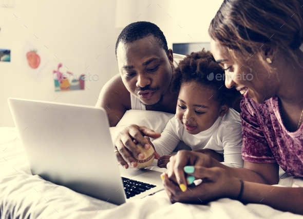 Black family lying on bed using computer laptop together in bedroom Stock Photo by Rawpixel