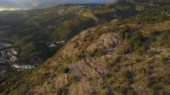 Aerial view of newlywed couple walks on a mountain in Montenegro at sunset alt