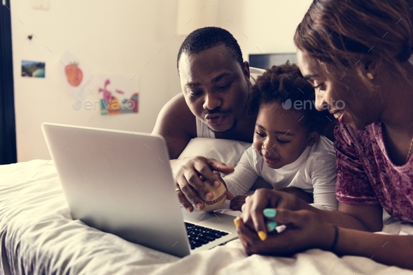 Black family lying on bed using computer laptop together in bedroom Stock Photo by Rawpixel