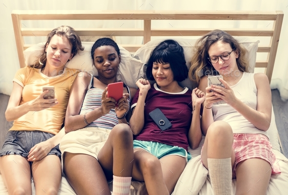 Group of diverse women lying on bed using mobile phones together Stock Photo by Rawpixel