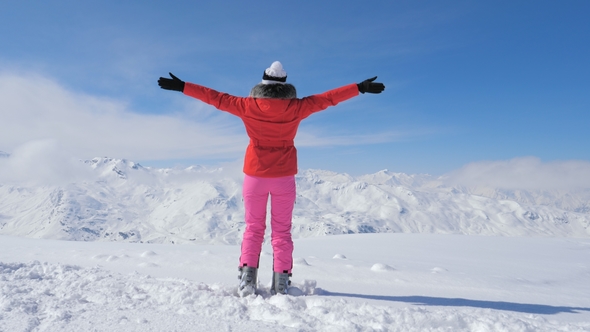 A Stylish Skier Woman On Peak Mountain, Raises Hands And Begins Spinning Around alt