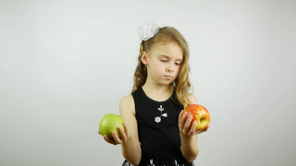 Very Beautiful Girl Holds a Red and Green Apple in Hands. Selects and Offers a Green Apple