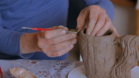 Professional Potter Making Pattern on Clay Mug with Special Tool in Workshop